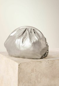 Silberne metallische Lederhandtasche mit einem gerafften oberen Teil, runder Form und Kettenriemen. Glatte Textur mit einem subtilen Glanz und gefältelten Details.