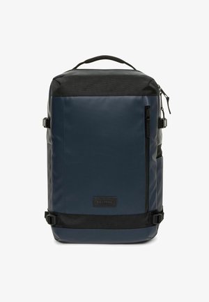 Granatowy plecak o gładkim wykończeniu, czarne akcenty i wyraźna forma. Posiada boczne klamry, przednią kieszeń na zamek oraz górny uchwyt.