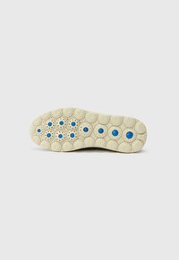 Shoe outsole features a textured cream rubber surface with circular patterns and blue accents in the center of some circles.