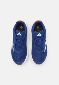 Scarpe sportive blu navy con tomaia in rete, strisce bianche e superficie testurizzata. Presentano un accento arancione brillante sul tallone e un interno nero.