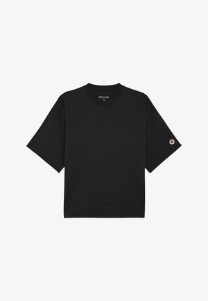 T-shirt noir à manches courtes avec col rond et petit patch circulaire sur la manche gauche.