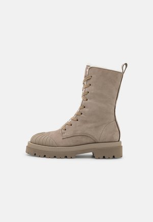 Botte beige montante à lacets avec semelle extérieure en caoutchouc épaisse et embout renforcé, dotée d’une languette arrière et d’une semelle texturée pour une meilleure adhérence.