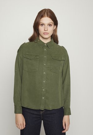 Camicia a maniche lunghe verde oliva con bottoni, due tasche sul petto, colletto strutturato e vestibilità leggermente rilassata. Tessuto morbido.