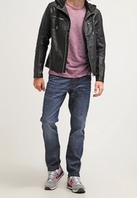 Musta nahkatakki, jossa on kaksi vetoketjullista taskua, purppuranvärisen paidan päällä. Yhdistetty tummansinisien farkkujen ja harmaiden tossujen kanssa, joissa on punaisia yksityiskohtia.