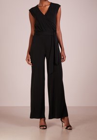 Svart omslagsdräkt med korta ärmar, djup V-ringning, vida ben och en knytbar midjesnodd, tillverkad av ett mjukt, stretchigt tyg.