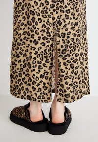 Maxikjole med leopardprint og sideslits, laget av mykt stoff. Kombinert med svarte slip-on sko med en myk fôr og leoparddetaljer.