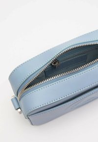 Borsa in pelle azzurro chiaro con chiusura a zip, dotata di hardware argentato, superficie testurizzata e cuciture dettagliate lungo i bordi.