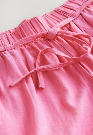 Shorts rosa in lino con una vita elastica, dotati di un cordoncino da annodare e una texture morbida. Il tessuto appare leggero e leggermente sgualcito.