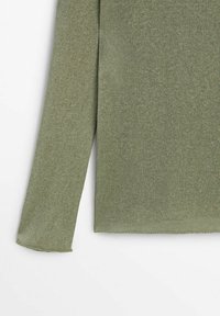 Pull tricoté vert olive avec un col rond, des manches longues et une surface légèrement texturée ; l'ourlet présente des bords bruts.