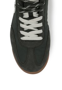 Baskets noires avec lacets blancs, semelle marron et détails en daim, vues de dessus.