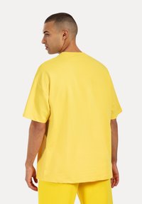Gele oversized t-shirt met korte mouwen, ronde hals en een gladde katoenstructuur, gedragen met bijpassende gele broek.
