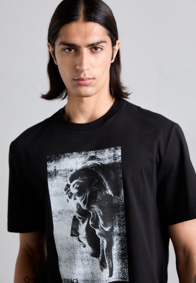 T-shirt en coton noir arborant une grande impression graphique en gris et blanc du profil d'une sculpture classique sur le devant.