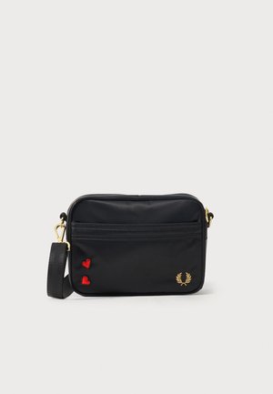 Μαύρη ορθογώνια τσάντα ώμου με χρυστό φερμουάρ, ρυθμιζόμενο ιμάντα, δύο κόκκινες καρδιές και χρυσό λογότυπο δάφνινο στεφάνι μπροστά.