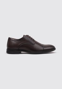 Zapato de vestir de cuero marrón con un acabado liso, detalles decorativos de broguing y una puntera redondeada, que cuenta con una suela de goma negra de perfil bajo y elegante.