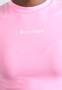 Różowa, dopasowana koszulka z gładkiego materiału, z małym, beżowym logo "Palm Angels" wyhaftowanym z przodu, o wysokim dekolcie.