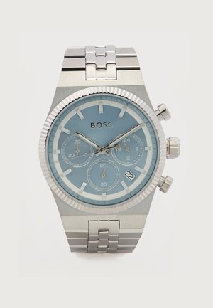 Zilverkleurig metalen polshorloge met lichtblauwe wijzerplaat, drie subdials, datumaanduiding bij 4 uur en "BOSS"-branding onder 12 uur.