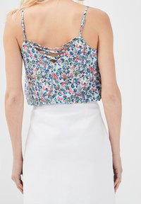 Débardeur à imprimé floral avec fines bretelles, présentant un dos en dentelle. Tissu léger aux couleurs bleu, rose et vert.