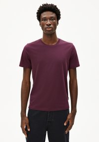 Maglietta a maniche corte color bordeaux con scollatura a girocollo, realizzata in morbido tessuto di cotone. Forma aderente con orlo senza cuciture e senza motivi visibili.