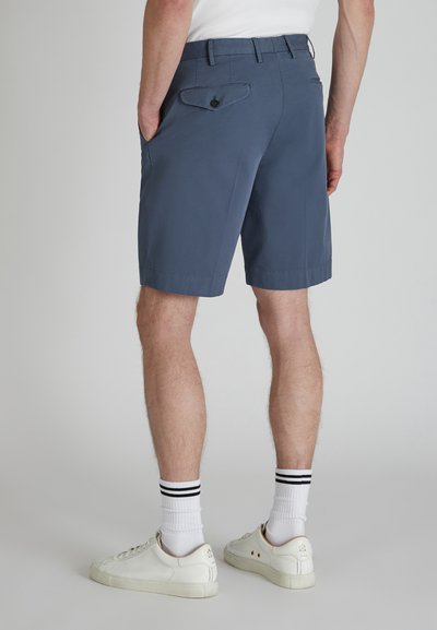 Pantaloni corti grigi da uomo con una vestibilità dritta, due tasche posteriori e una texture liscia. Abbinati a sneakers bianche e calzini a righe nere.