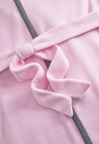 Soft pink fleece fabric with a matching belt tied in a knot over a contrasting dark gray seam.
