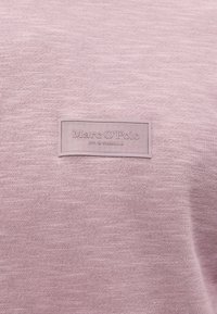 Rozā kokvilnas džemperis ar teksturētu audumu un taisnstūra birku, uz kuras priekšpusē ir izšūts "Marc O'Polo".