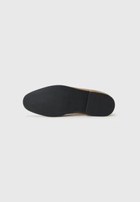 Suela de zapato con un fondo de goma negra lisa y un borde de ante marrón. Diseño plano sin patrones o acentos visibles.