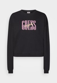 Sudadera corta negra con el logo "GUESS" en letras grandes de color rosa y amarillo. Tejido suave y texturizado con mangas largas y puños de canalé.