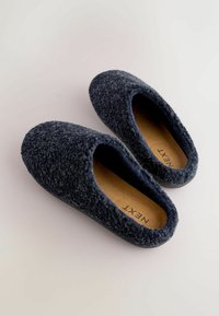 Dark blue textured slippers with a soft, fuzzy exterior, open back, and brown insole featuring brand name "NEXT."