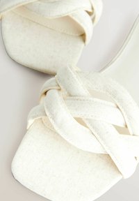 Sandales à talons blancs avec un dessus tissé en tissu texturé. Bout carré avec une semelle lisse et minimaliste.
