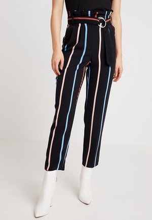 Zwarte broek met hoge taille en verticale roze, blauwe en bruine strepen, met een riem met zilveren gesp, gecombineerd met witte enkellaarsjes.