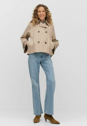 Beige double-breasted cropped jacket with large buttons, paired with light blue straight-leg jeans and brown heeled ankle boots.