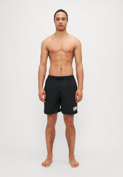 Shorts de bain noirs avec une taille élastique, un cordon de serrage ajustable et un logo blanc imprimé sur le bas à gauche. Texture lisse.