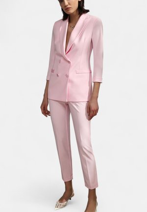 Blazer rosa su misura con design doppiopetto, rever a punta e pantaloni slim-fit coordinati. Tessuto testurizzato con tasche e fessure laterali.