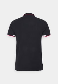 Svart polo skjorta med korta ärmar, kontrasterande röda och vita detaljer på kragen och ärmsluten. Slät textur, klassisk passform.