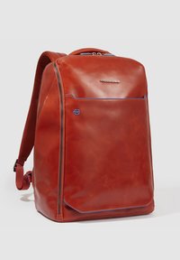 Rode leren rugzak met een gladde textuur, een voorkantzak, blauwe stikselaccenten en verstelbare, gevoerde schouderbanden.
