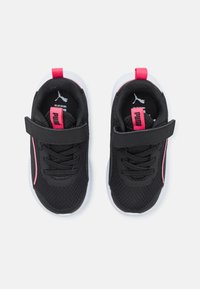 Chaussures de sport noires avec une tige en maille, accents roses, bande réglable et semelle blanche. Présente un matériau texturé et un embout renforcé.