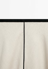 Tissu en lin beige avec une bande horizontale noire en haut et une ligne noire verticale au centre.