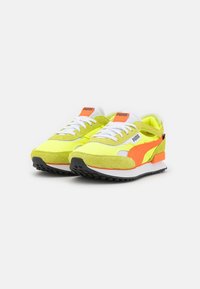 Limettengrüne Puma-Sneaker mit weißen Schnürsenkeln, orangefarbenen Akzenten und schwarzen Sohlen. Sie bestehen aus Wildleder und Mesh-Materialien im Retro-Design.