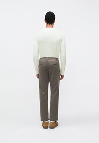 Jasnoszara koszula z długim rękawem, zestawiona z szarymi sztruksowymi spodniami i brązowymi butami, o prostym kroju i luźnym fasonie.