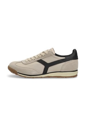 Zapatilla beige hecha de ante y malla, con un diseño de franjas diagonales negras, media suela blanca y suela exterior de goma texturizada.