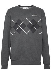Grå sweatshirt med långa ärmar, rund halsringning, med ett diamantmönster i svart och vitt över bröstet, och Adidas-logotypen ovanför mönstret.