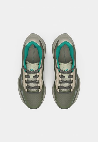Un par de zapatillas deportivas verdes y beige con cordones grises y forro interior turquesa, vistas desde arriba sobre un fondo blanco.