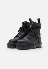 Mustad musta nahast ankle boots, millel on jäme kummist tallad. Omab kattuvaid paelu, kaht lukuga detaili ja tõmbenööre.