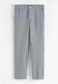 Pantalon gris en tissu texturé. Il est doté d'une ceinture élastique, de poches avant et d'un petit bouton métallique à la taille.