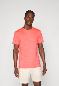 Camiseta de manga corta de color coral con un sutil patrón de camuflaje, fabricada en tejido ligero, con cuello redondo y corte regular.