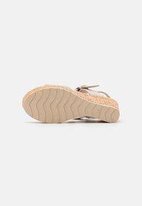 Beige wedge sandaal met een gestructureerde kurken zool, flexibele rubberen onderkant en een glad bovenwerk met een vetersluiting.