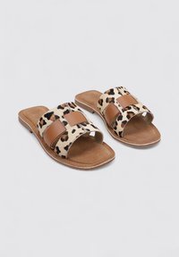 Chanclas de piel sintética marrón con estampado de leopardo y una plantilla suave y plana. Superficie ligeramente texturizada; diseño abierto en la parte delantera.