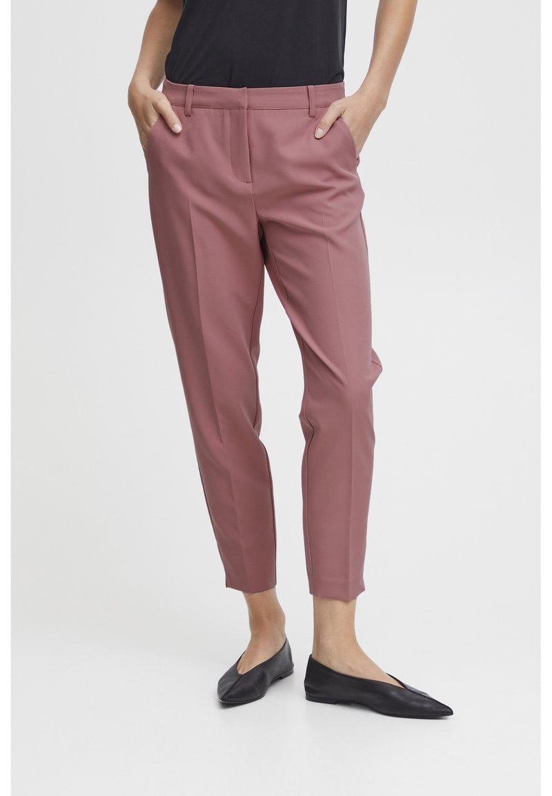Dusty rose tailored pants with a straight cut, front pleats, and side pockets, paired with black slip-on shoes. Smooth fabric texture.