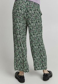 Blommönstrade byxor med grön bakgrund, vita och rosa blommor, vida ben och ett mjukt, lätt tyg.