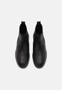 Botas de tobillo de cuero negro con una superficie lisa, punta redondeada, paneles laterales elásticos y una lengüeta trasera para ponerlas y quitarlas fácilmente.